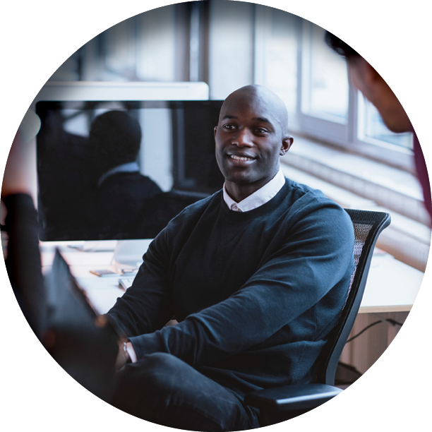 smiling businessman with legs crossed seated in front of a computer